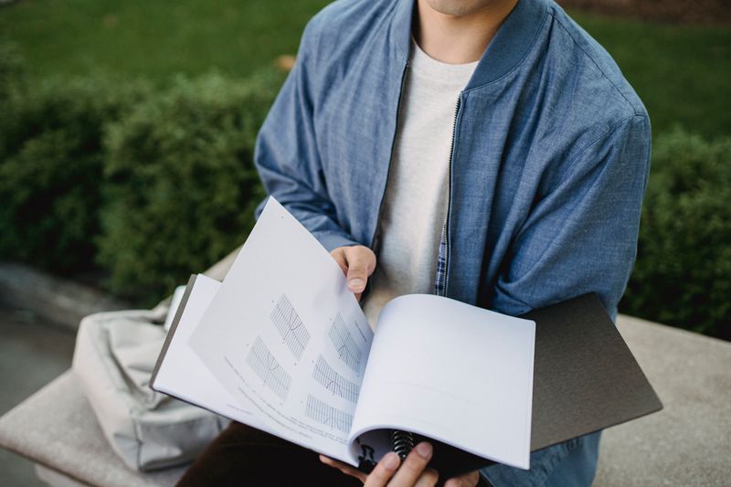Student reading through a printed research paper to check originality