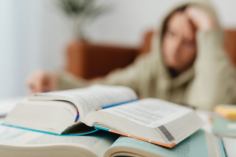 Stressed student studying with open textbooks for a difficult AP exam