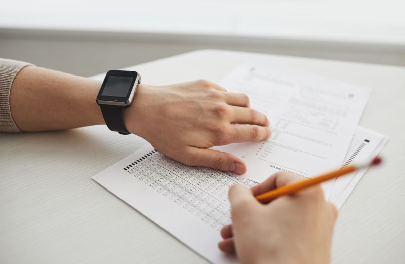 Hand wearing a smartwatch while filling out a form near a deadline