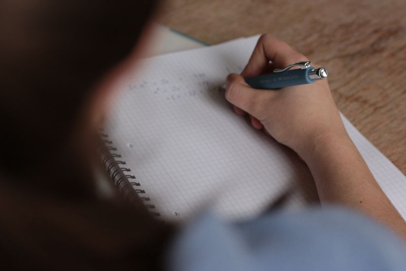Hand writing a draft in a notebook while checking a word count