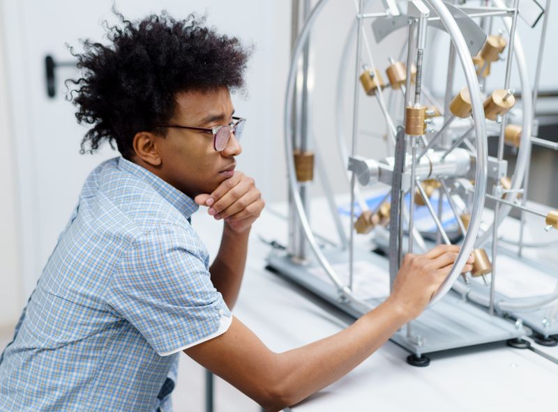 Student examining lab equipment as part of an alternative research path to the cosmos summer program