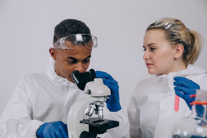 Two researchers examining samples under a microscope, similar to a Dallas high school research internship