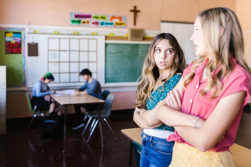 Two high school students discussing team eligibility for the Diamond Challenge in a classroom