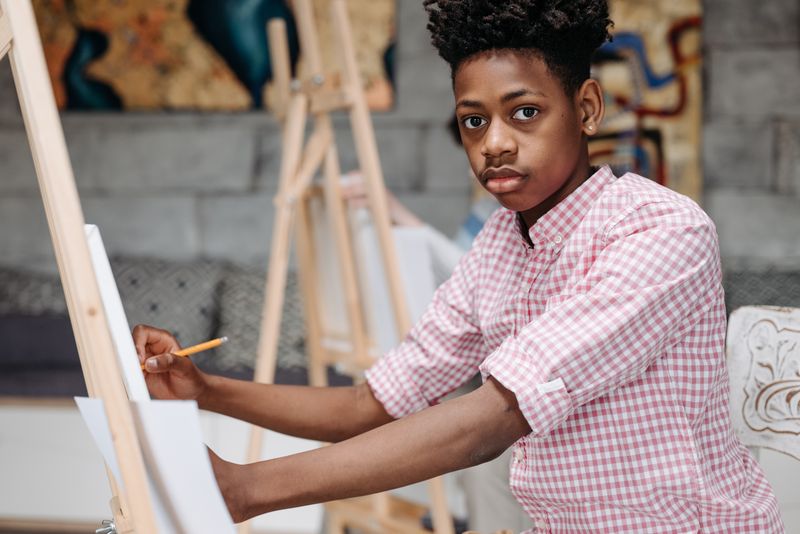 Teen student painting on an easel as part of a free arts summer program