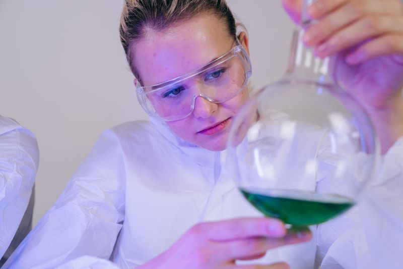Student examining a lab flask as part of a free STEM summer research program