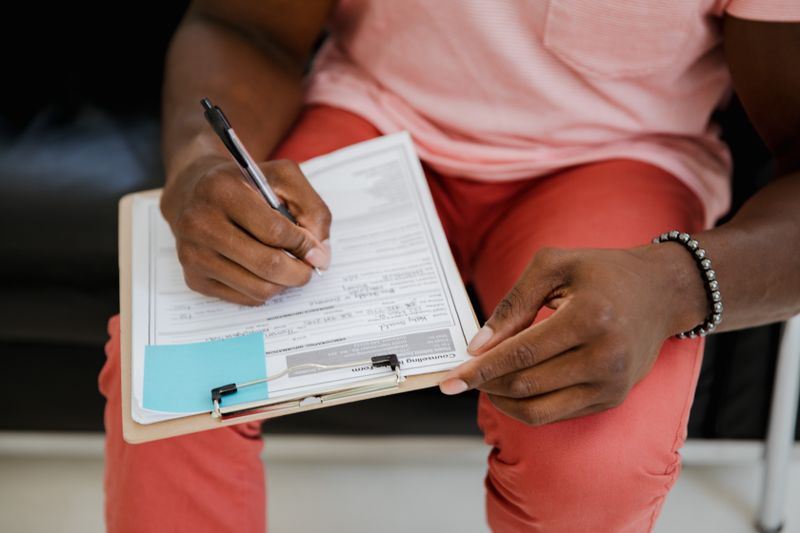 Close-up of hands filling out an application form on a clipboard