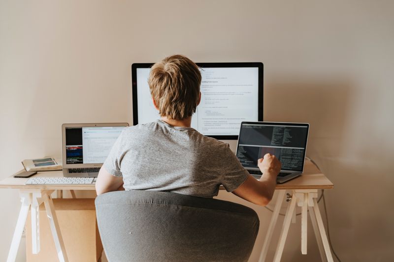 Student working at multiple computer screens building programming skills