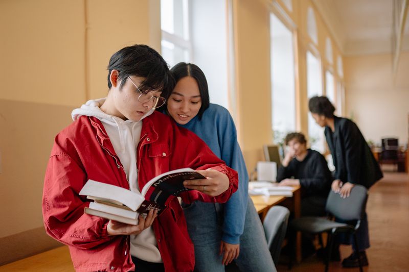 High school student reading an academic journal at a library table