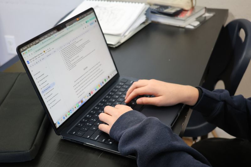 Hands typing a college application resume on a laptop
