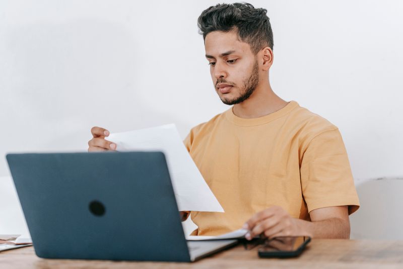 Student reviewing paperwork next to a laptop to confirm a recommendation letter is matched