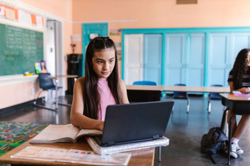 High school student writing a research paper on a laptop at home