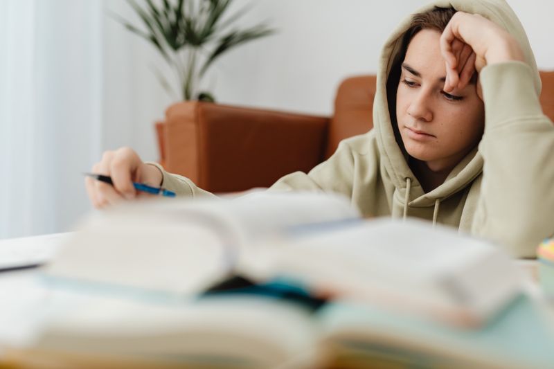 Focused high school student reading and writing independently for a research project