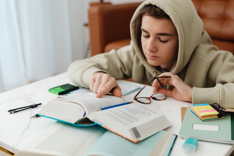 Student reading through a highlighted book while taking research notes