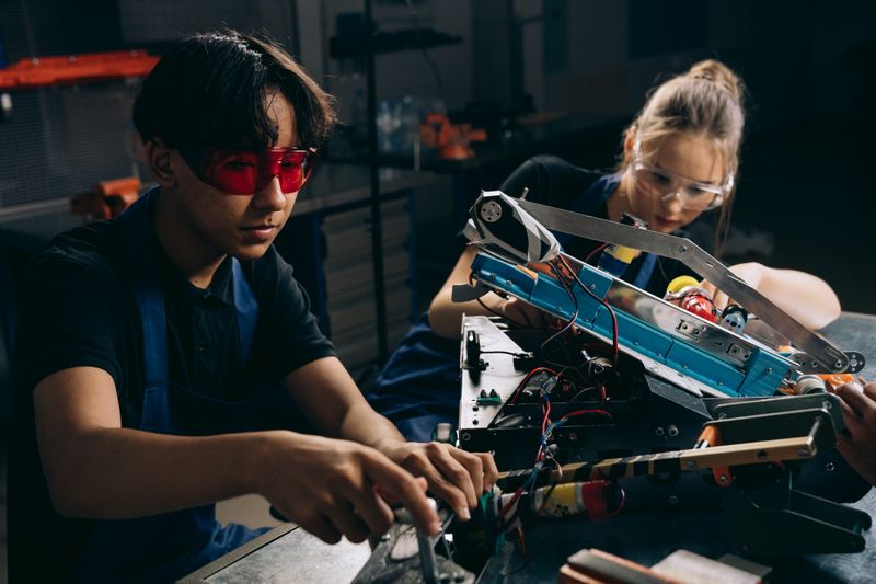 Two young engineers working on robotic equipment, similar to New Jersey Governor's School engineering projects