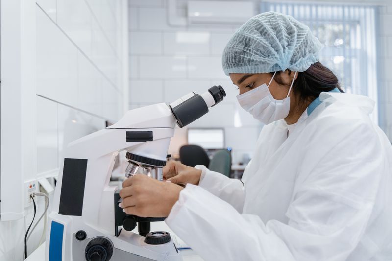 Researcher examining samples under a microscope in a lab, like Princeton's free Laboratory Learning Program