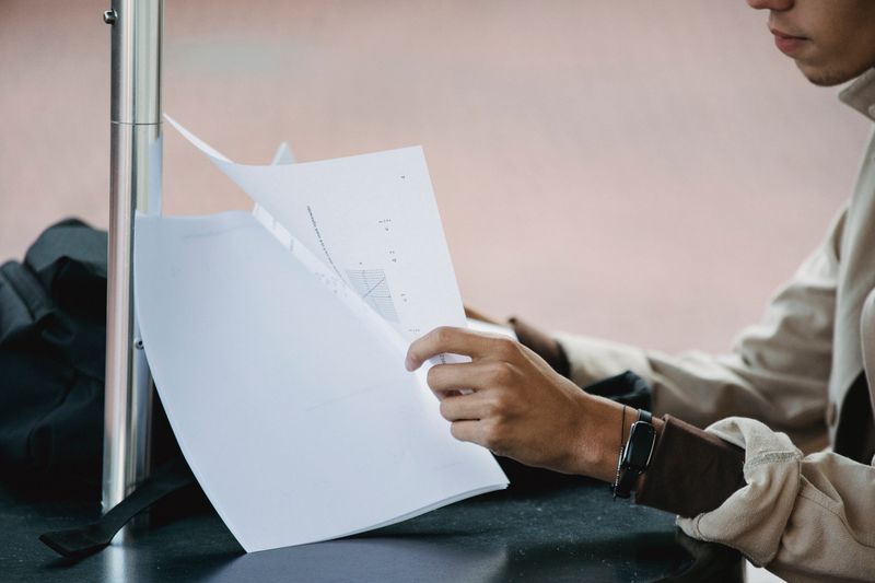 High school student reading academic research papers and taking notes for a research project
