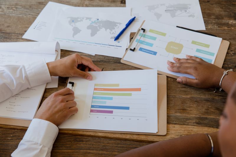 Hands pointing at a bar chart while reviewing research results data