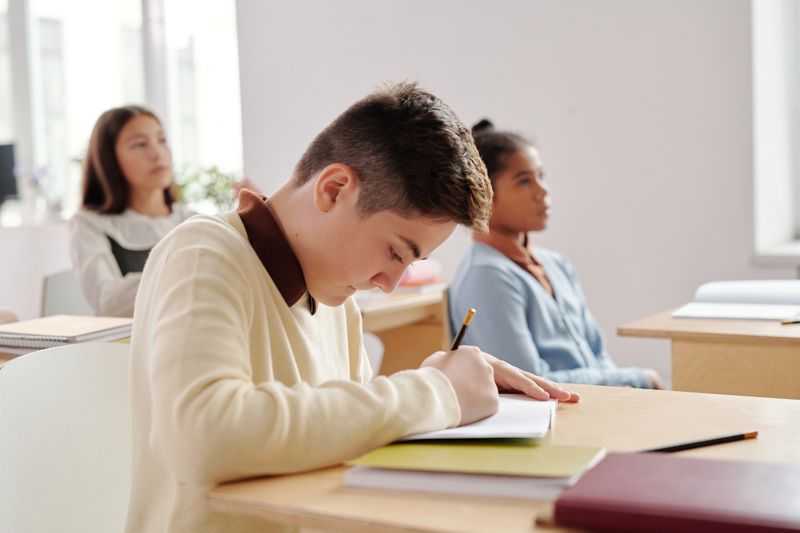 Student writing in a classroom comparing a resume to the Common App activities section
