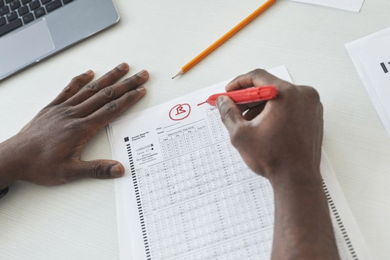 Teacher grading a multiple choice Science Olympiad practice test with a red pen