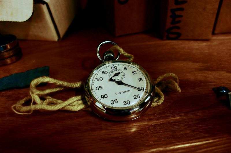 Silver stopwatch on a wooden table for timing a Science Olympiad practice test
