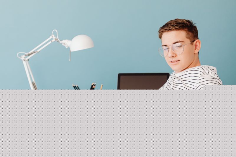 Student sitting at a desk deciding whether to wait before submitting a college application