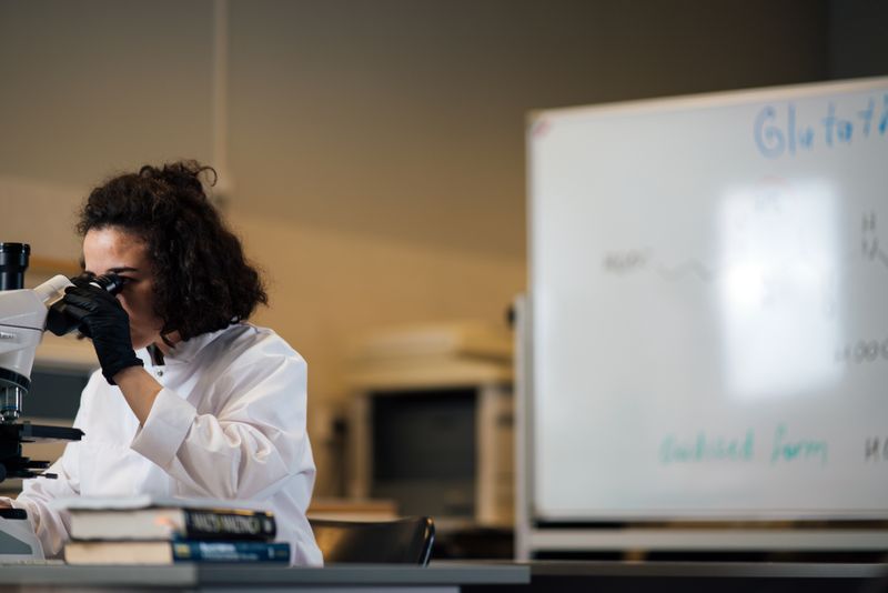 Student examining a sample under a microscope in a research lab setting
