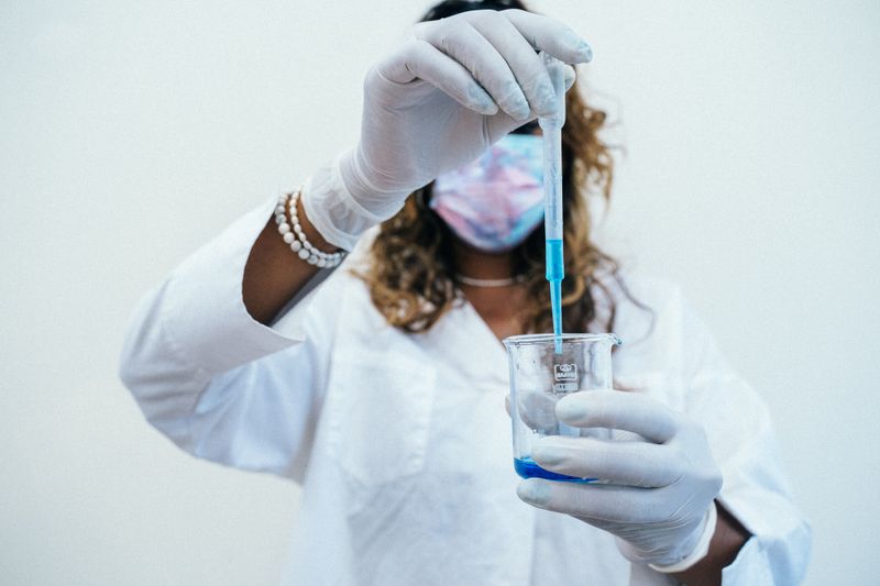 Student in gloves and mask pipetting a solution during biomedical research
