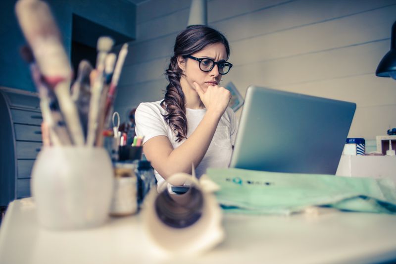 Student thinking carefully before writing at a laptop