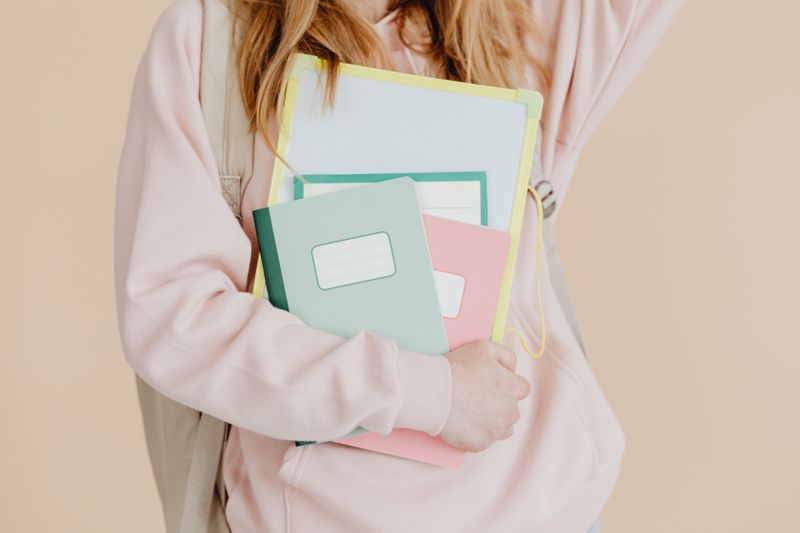 Student holding folders and notebooks representing what to include on a college application resume