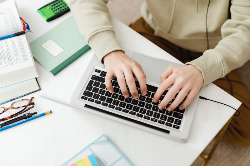 High school student writing a research paper on a laptop after completing a research project