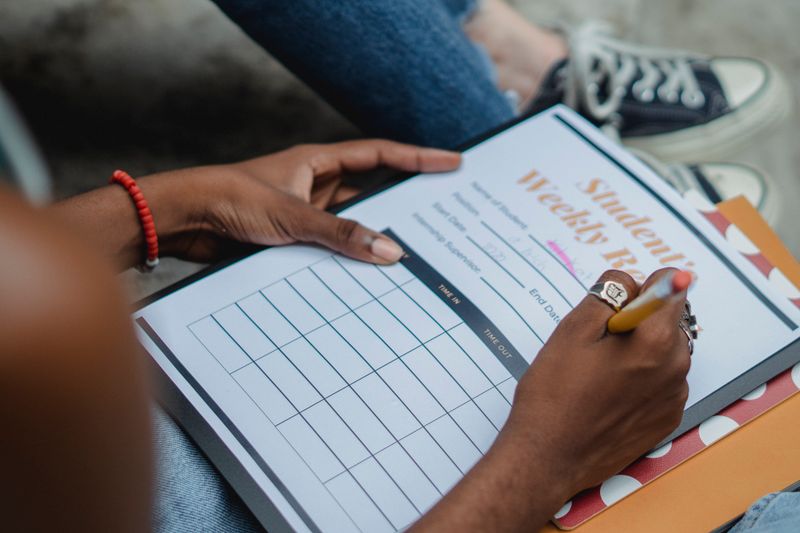 Student writing a research paper outline in a notebook